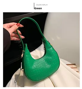Detail view of green faux crocodile crescent bag with smooth gold hardware