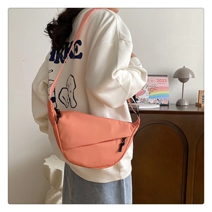 Détail du sac demi-lune en nylon orange pêche porté avec un sweat à capuche blanc décontracté