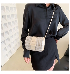 Détail du sac bandoulière en tweed crème avec boucle décorative et bandoulière chaîne dorée
