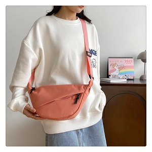 Gros plan sur un sac bandoulière en nylon rose corail avec bandoulière réglable
