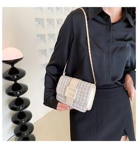 Détail d'un sac bandoulière en tweed crème avec chaîne dorée et boucle en cuir sur modèle