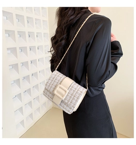 Détail du sac bandoulière en tweed avec boucle en résine et chaîne porté par un modèle