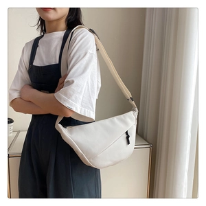 Gros plan du sac banane en nylon crème avec cordon noir et bandoulière réglable