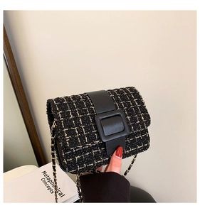 Gros plan sur la texture en tweed noir et la bandoulière chaîne dorée d'un sac