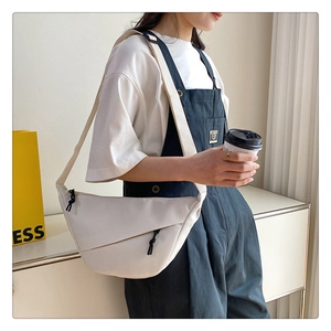 Détail d'un sac besace blanc cassé en nylon avec large bandoulière et fermeture zippée