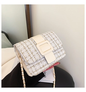 Gros plan d'un sac bandoulière en tweed beige avec chaîne dorée et grande boucle carrée