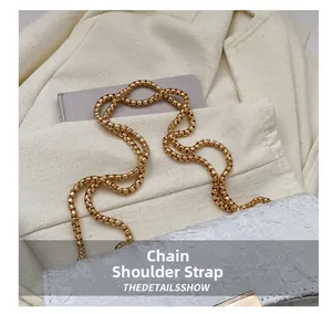 Detail view of the silver pleated texture and chunky gold chain strap on the bag