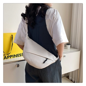 Détails du sac croissant en nylon beige montrant la texture souple et le zip à cordon