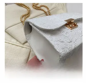 Detailed macro view of white pleated fabric texture with gold metal buckle and chain strap