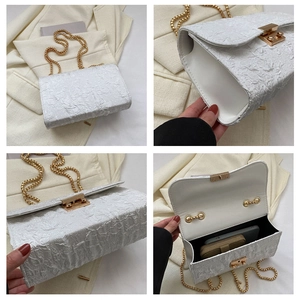 Detail view of white pleated oxford bag featuring gold chain strap and turn-lock closure