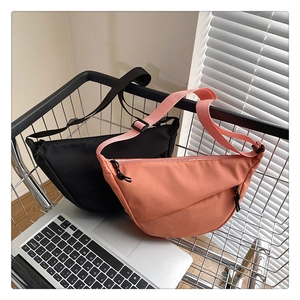 Détail de sacs bandoulière demi-lune en nylon noir et pêche dans un panier métallique