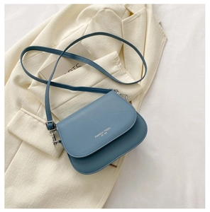 Détail du sac selle bleu en cuir mat avec lettrage doré de tendance mode