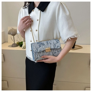 Light blue pleated chain bag detail with gold metal lock and textured fabric finish
