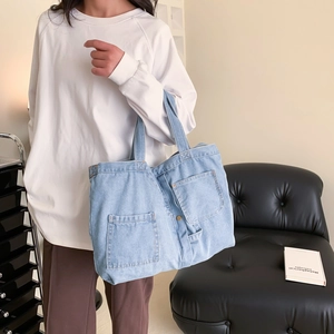 Minimalist light blue denim tote bag with pocket details shown in a lifestyle setting