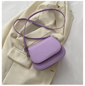 Détail du sac bandoulière violet avec logo argenté sur fond de textile texturé
