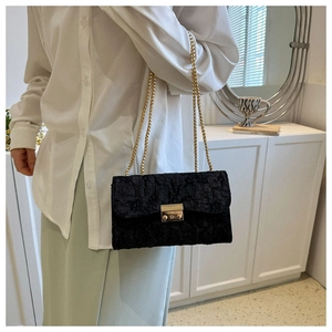 Detail of black pleated fabric texture with gold chain strap and metallic buckle