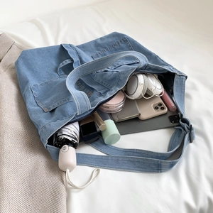 Spacious light blue denim tote bag with external pocket shown with daily essentials