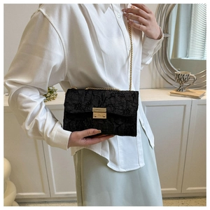 Detailed shot of black pleated crossbody bag with gold chain strap worn by a model