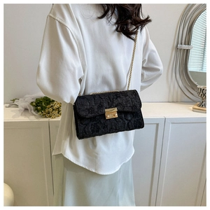 Detailed side view of black jacquard crossbody bag with gold chain on model's shoulder