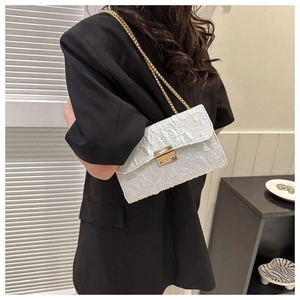 Detail of white pleated texture fabric on shoulder bag with gold chain and metal lock