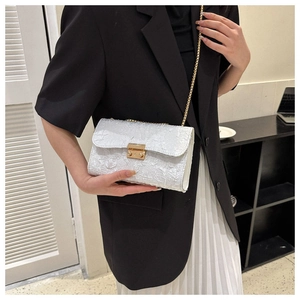 Detailed shot of a white pleated oxford fabric crossbody bag with a gold chain and buckle