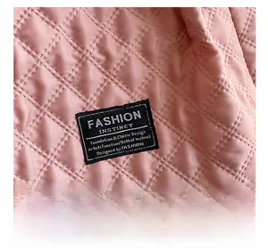 Detail of pink quilted nylon fabric with diamond stitching and black woven brand label