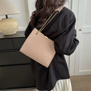 Beige crocodile embossed chain tote bag worn by a model in a minimalist setting