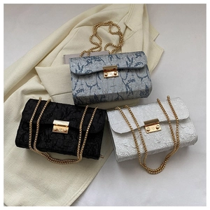 Detailed view of three crossbody bags with chain straps and gold hardware on a beige blazer