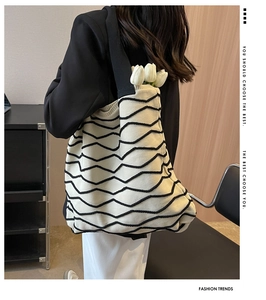 Detail of knit shoulder bag with black wavy relief patterns and white tulip decoration