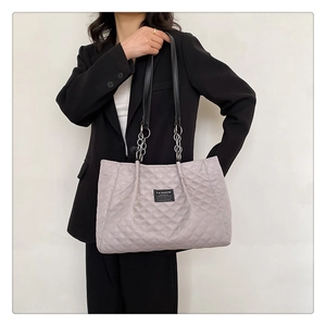 Close-up of quilted nylon tote bag with black leather handles and silver chain detail