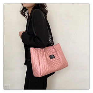 Detail of light pink quilted nylon tote bag featuring chain strap and fashion label