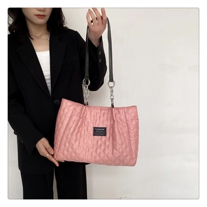 Detail of pink quilted nylon tote bag featuring silver chain straps and fashion label