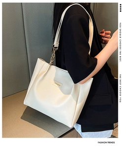 Detail of white faux leather tote with fashion label and metal chain shoulder strap