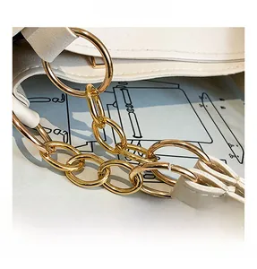Detailed close-up of premium gold metal chain strap on white leather tote bag
