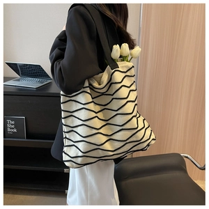 Detail of knit tote bag featuring black wavy stripes on cream white crochet fabric