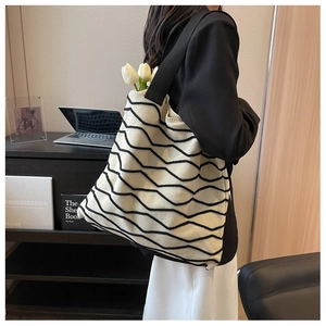 Detail of knit shoulder tote bag with black wave pattern styled on model in office