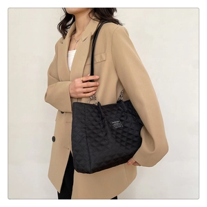 Detail of black quilted nylon tote bag with silver chain strap and fashion label