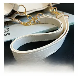 Detail of white leather shoulder strap with precise stitching and gold metal chain links