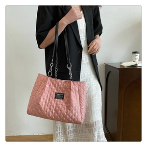 Close-up of pink quilted nylon tote bag with black fashion tag and chain shoulder strap