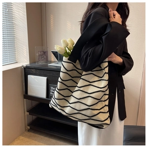 Detail of soft off-white knit tote bag with black wavy stitching and wide strap
