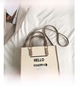 Détail du sac fourre-tout en toile crème avec poignées brunes et imprimé texte
