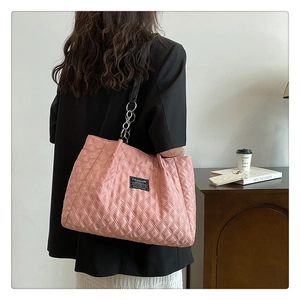 Pink quilted nylon tote bag featuring black shoulder straps and a central fashion patch