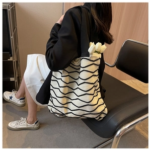 Detail of knit tote bag featuring black and white wave pattern with a wide shoulder strap