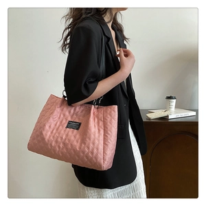 Detail view of pink quilted nylon tote bag with fashion tag and black shoulder strap
