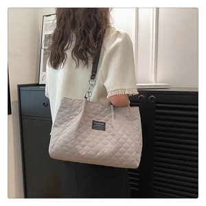 Close-up of grey quilted nylon tote bag with metal chain strap and black woven label