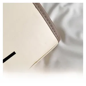 Gros plan sur le sac fourre-tout en cuir blanc cassé avec bords bruns et coutures fines
