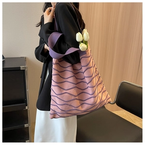 Side view of pink knitted tote bag with purple wavy texture and wide shoulder strap
