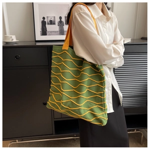 Detail shot of green knitted tote bag with yellow 3D wave texture and soft shoulder strap