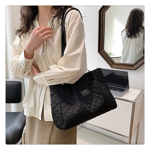 Detail of black quilted nylon tote bag with fashion label showing spacious capacity