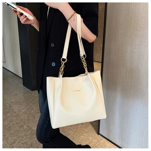 Detail of off-white tote bag featuring gold chain strap and FASHION leather patch